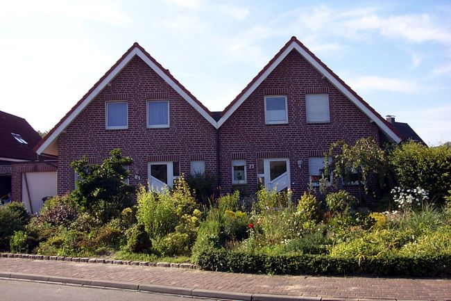 Ein hbsches Doppelhaus mit einem stark bepflanzten Beet
