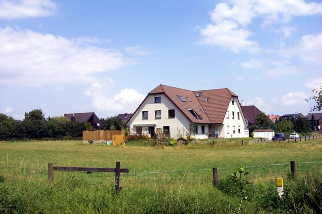 Blick ber eine Pferdewiese auf ein hbsches Haus