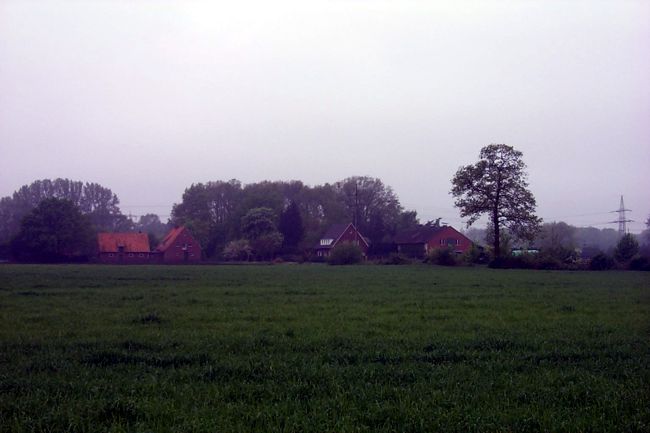 Blick ber ein Feld auf einen Bauernhof
